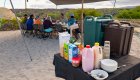 Appetizer table set up with milk, juice, water, cutlery, and bowls and plates at a campsite in the Galapagos