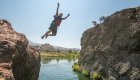Kid cliff jumping off a basalt boulder into the Deschutes River in Central Oregon