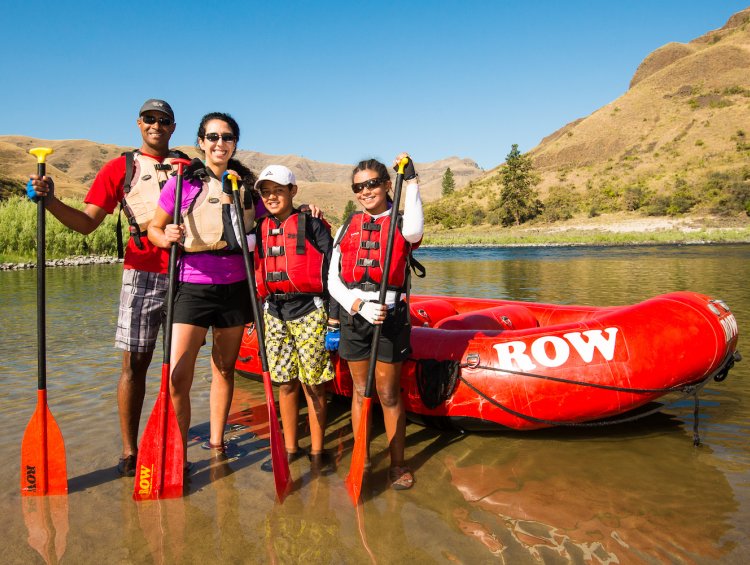 A family smiling for a photo in front of a red raft