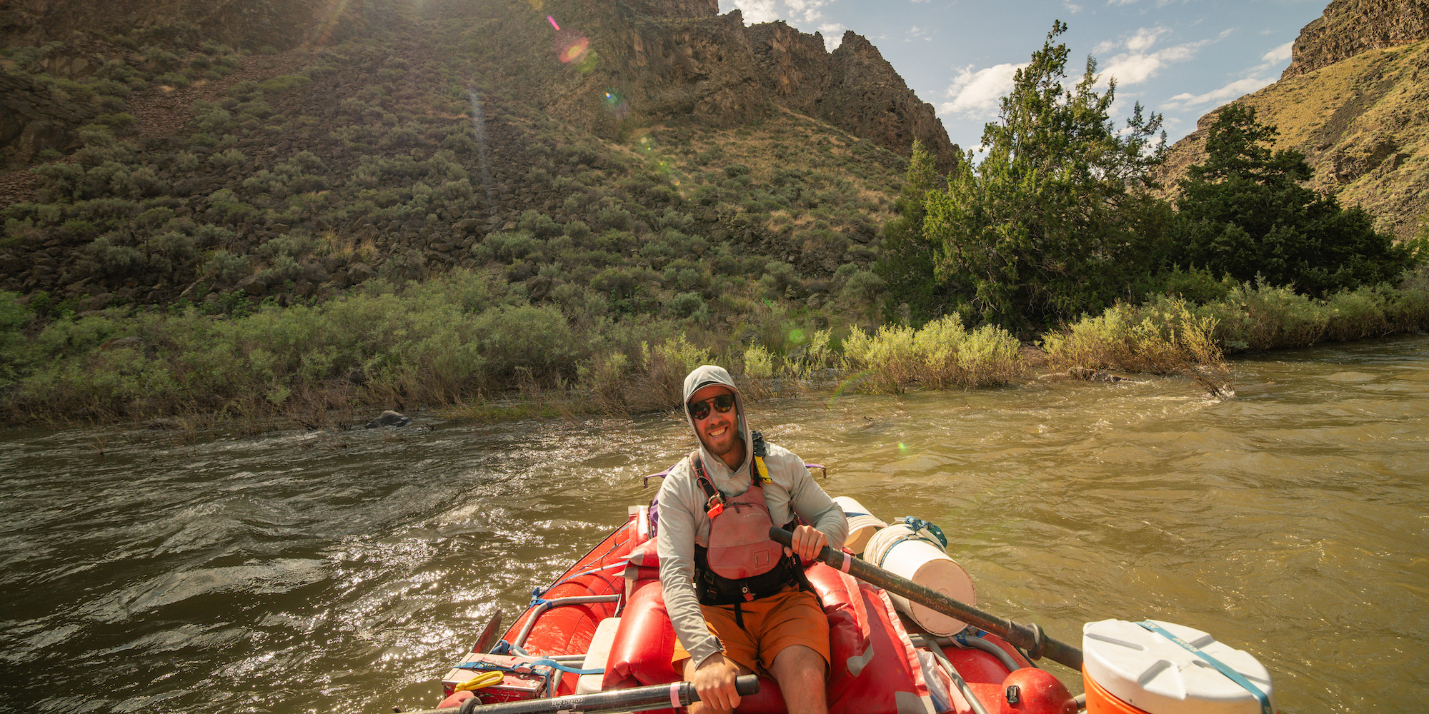 River guide wearing a sun hoodie while rowing a boat on the Bruneau River