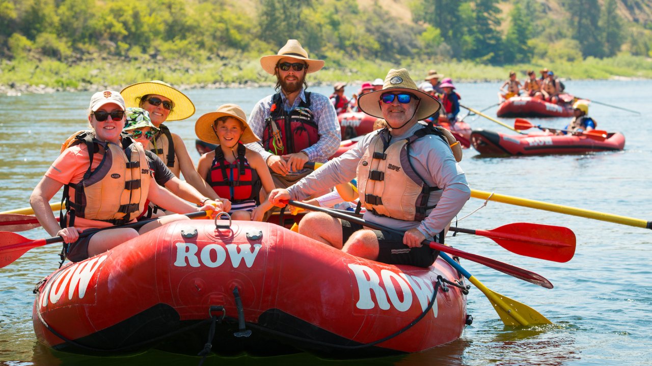 Family smiling on a red whitewater raft in Idaho