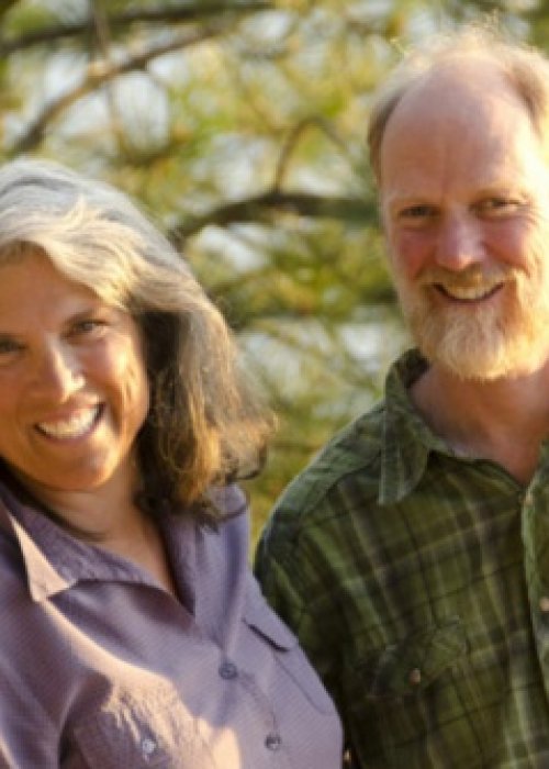 smiling couple with trees in the background