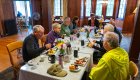 A group of older adults enjoying a meal together inside a cozy wood-paneled lodge, sharing stories and laughter after a day of adventure.