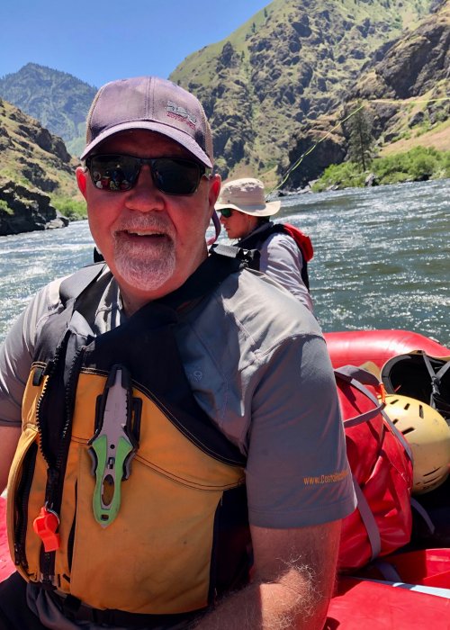man in yellow pfd on red whitewater raft