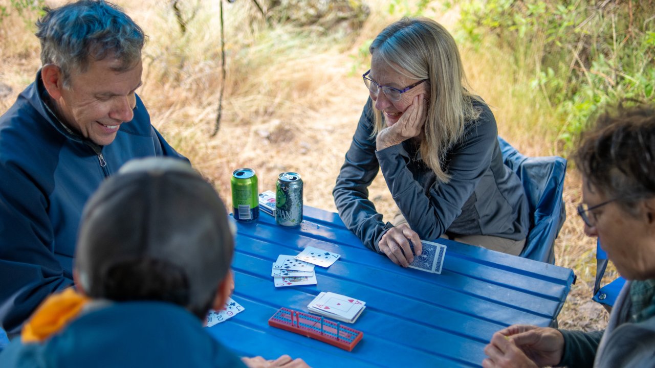 A group of people sitting around a blue table playing a game of cribbage