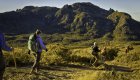 Hikers with backpacks walking through a sandy trail amongst desert mountains