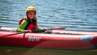 Young rafter paddling an inflatable kayak on Idaho’s Clearwater River during a sunny summer day, wearing a yellow helmet and red life jacket with ROW Adventures logo visible — perfect family-friendly rafting trip in Idaho.