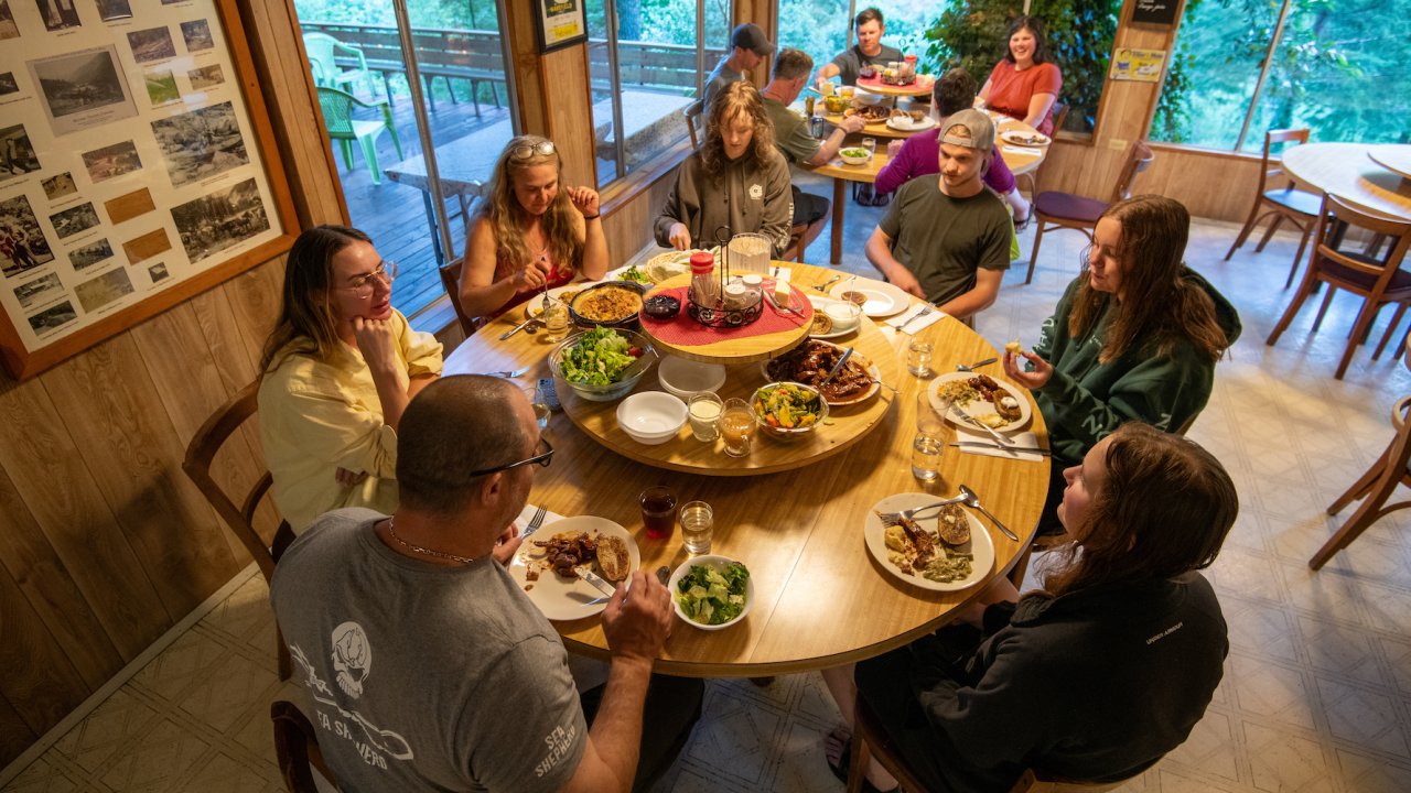 People gathered around a table at Marial Lodge while rafting the Rogue River
