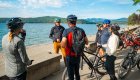 Group of people beside their bikes by a body of water conversing on a sunny day on a chartered e bike tour