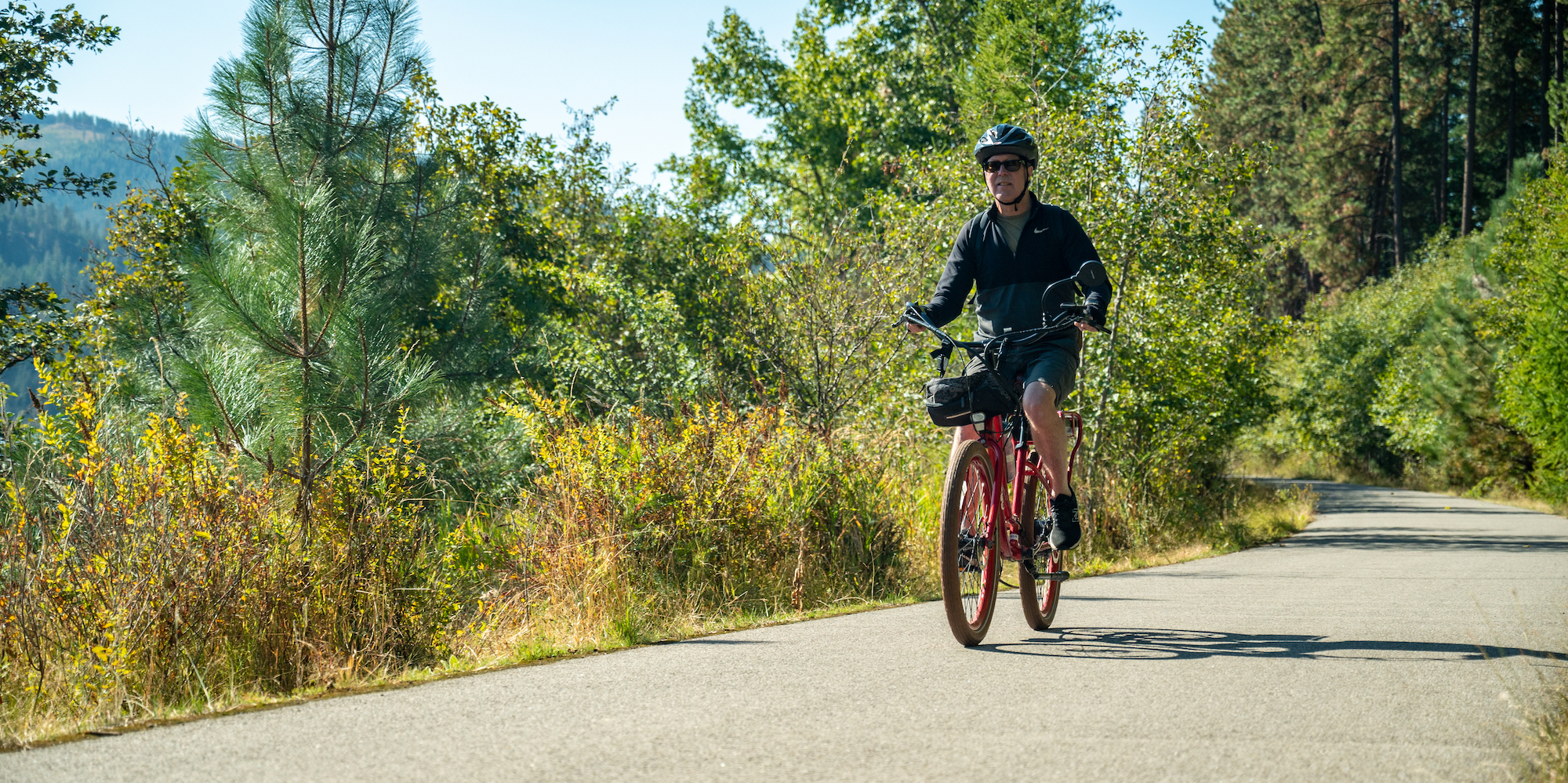 Man pedaling an e-bike on a paved trail in North Idaho