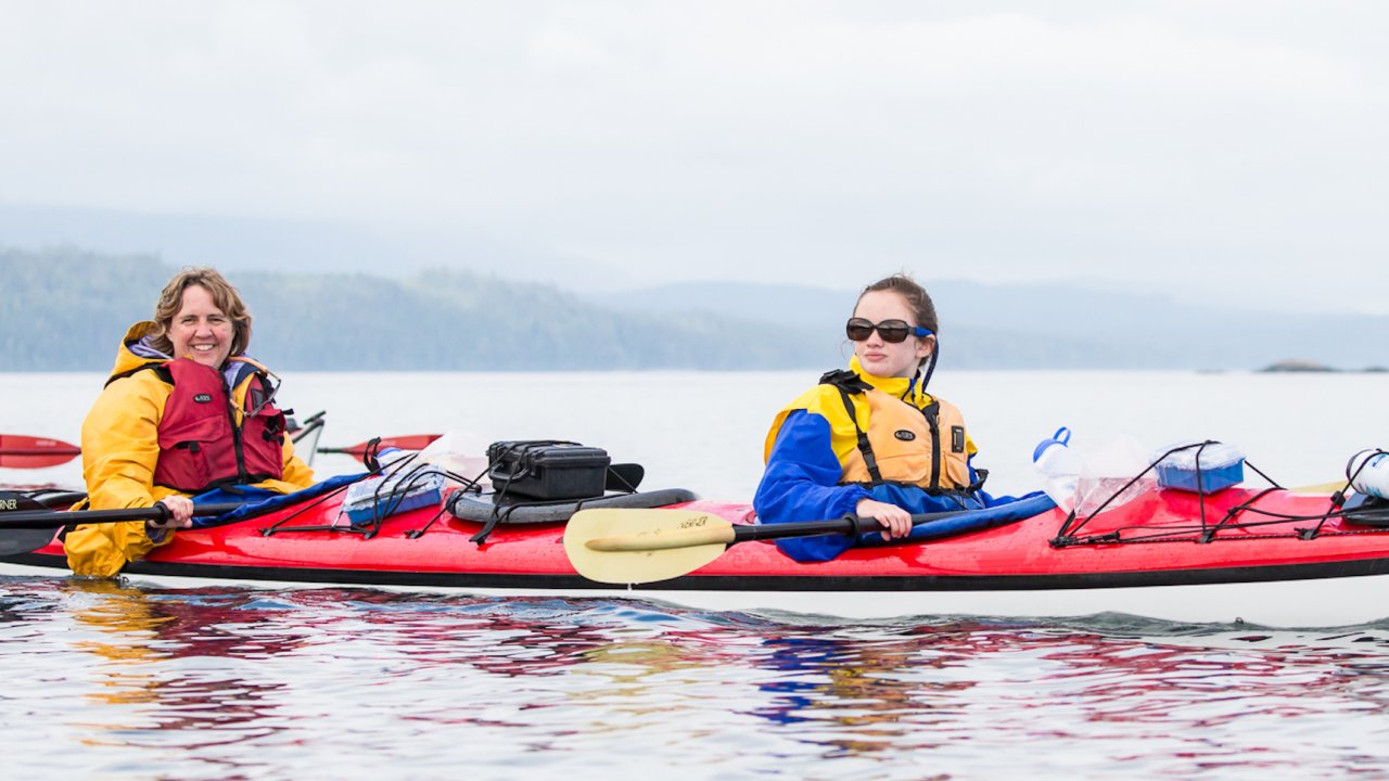 A mom and daughter in a tandem sea kayak in British Columbia