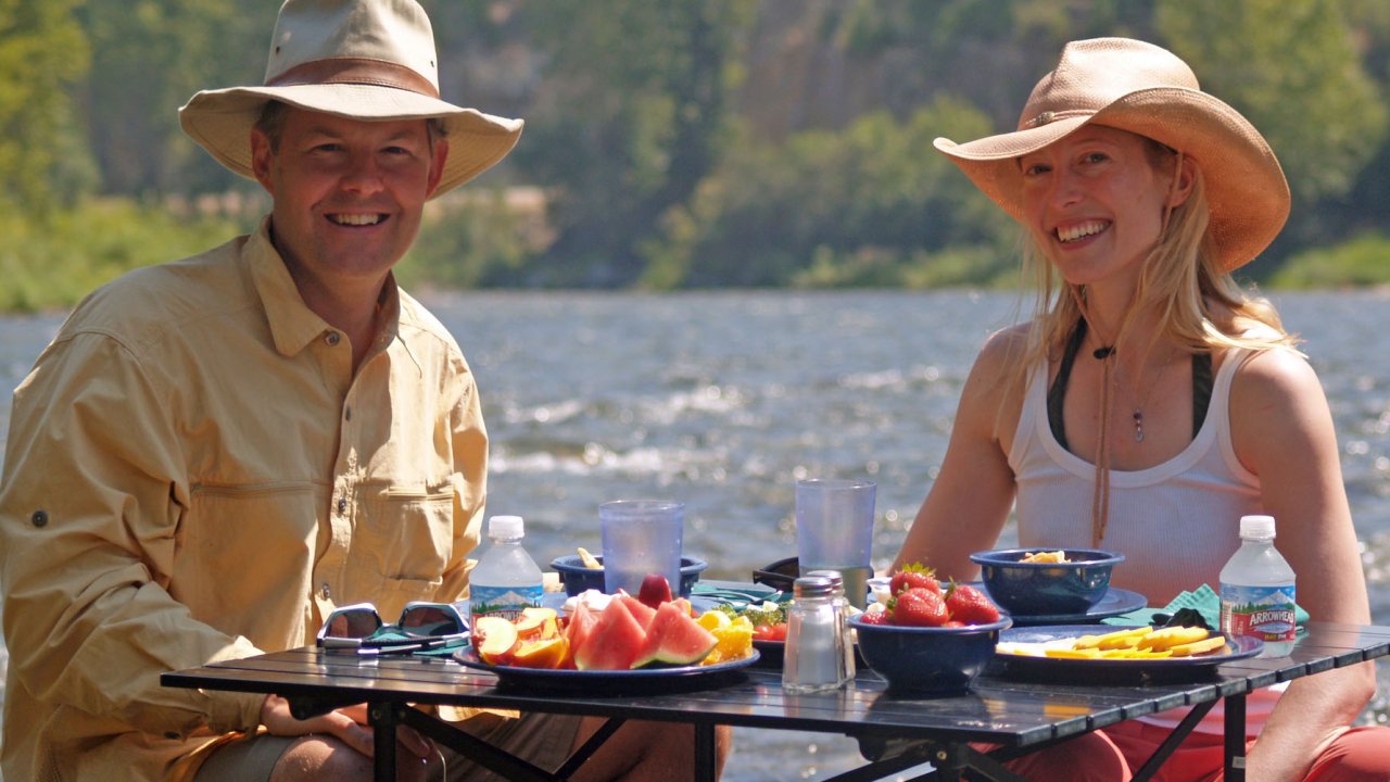 Happy anglers eating lunch on the river while on a guided fly fishing tour