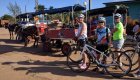 Three women standing next to their bikes in front of horse and garages on the street in Cuba