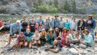 Happy rafting group posing by the Middle Fork of the Salmon River in Idaho after a multi-day whitewater adventure.