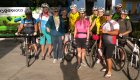 A group of people wearing helmets standing next to a fleet of bikes smiling in the sun in Cuba