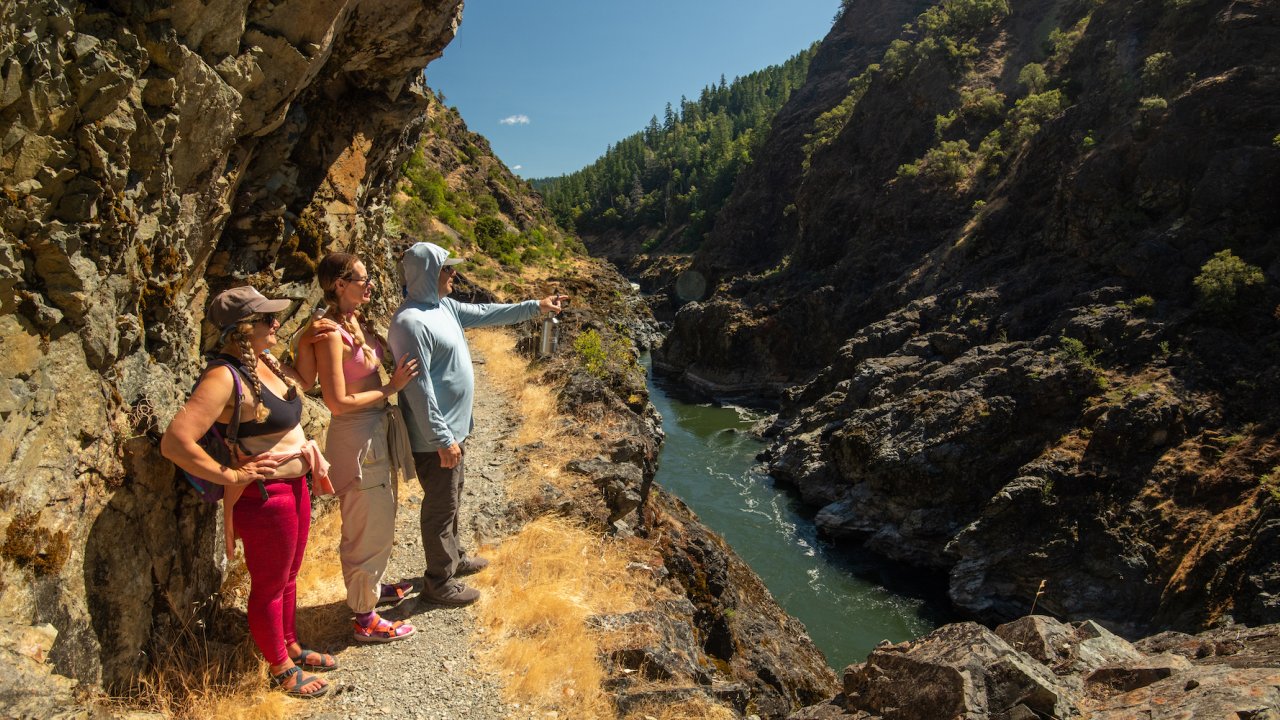 Three people observing something from a viewpoint on a hike