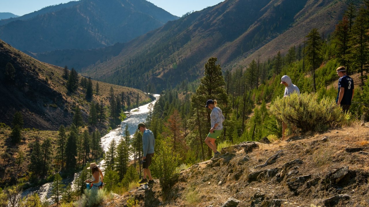 Group hiking along a scenic ridgeline overlooking the Middle Fork of the Salmon River on a multi-day Idaho rafting and hiking adventure.