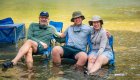 Family relaxing with chairs in the water during a main Salmon River rafting trip in Idaho.