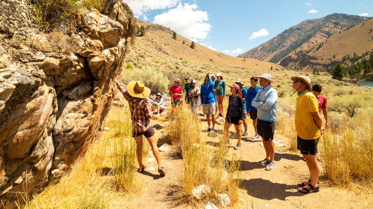 Rafting guide explaining ancient Native American pictographs to a group along the Middle Fork of the Salmon River in Idaho's Frank Church Wilderness.