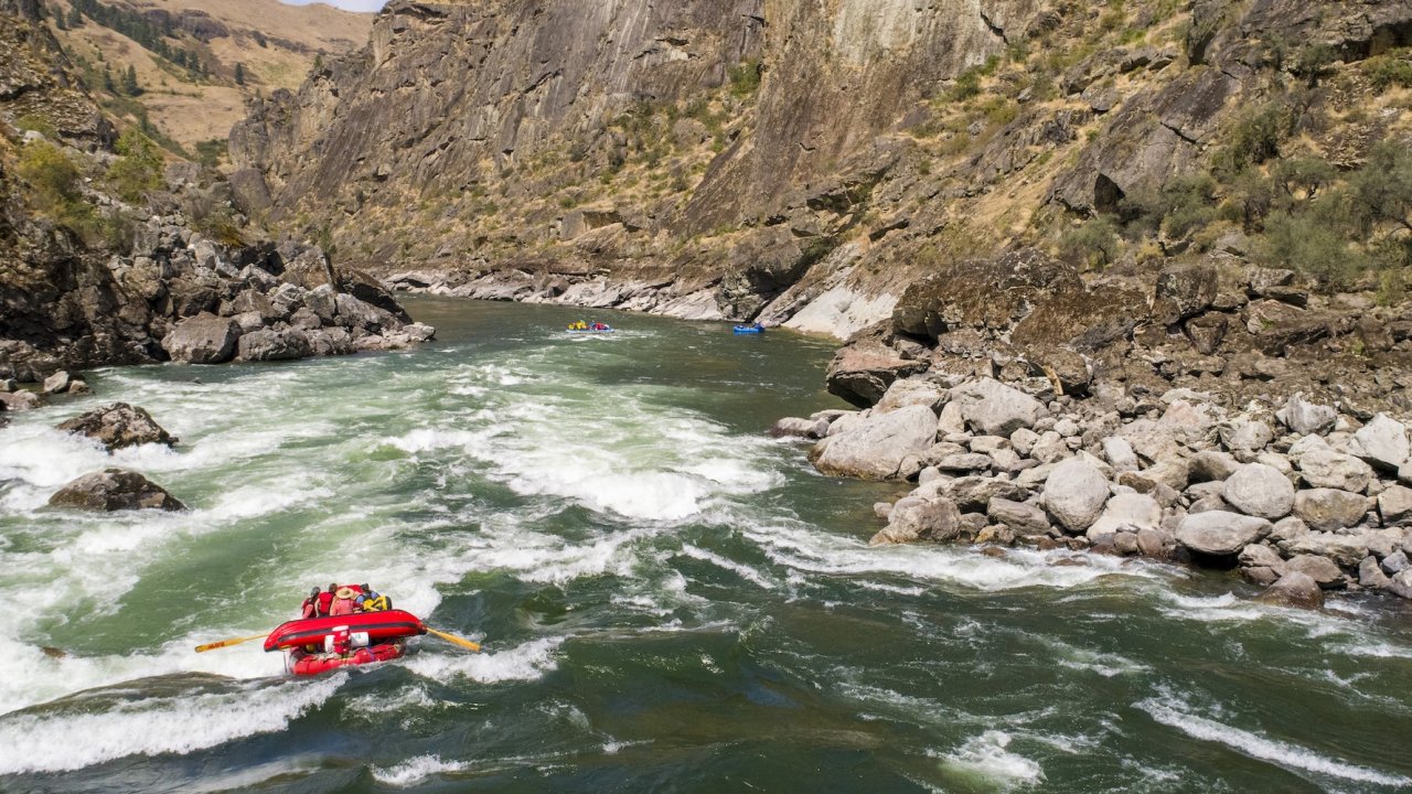 Raft navigating whitewater rapids through a rocky Idaho canyon.