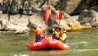people giving a paddle high five in a red raft