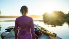 Person overlooking a dock full of sea kayaks along the Pacific Ocean at sunset