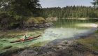 Kayaker moving through a narrow channel over crystal clear waters in British Columbia