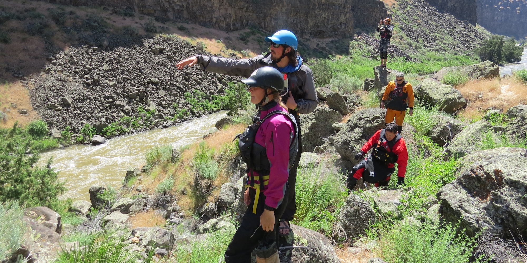 Guides scout a rapid from the bank of the river.
