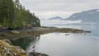 Sea kayakers leaving shore on a moody morning in British Columbia