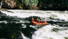 A red raft enters a rapid moving downstream on the Lochsa River