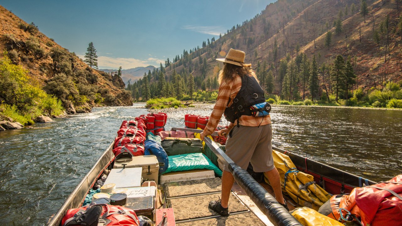 Man driving the legendary sweep boat down the Middle Fork Salmon River on a sunny day