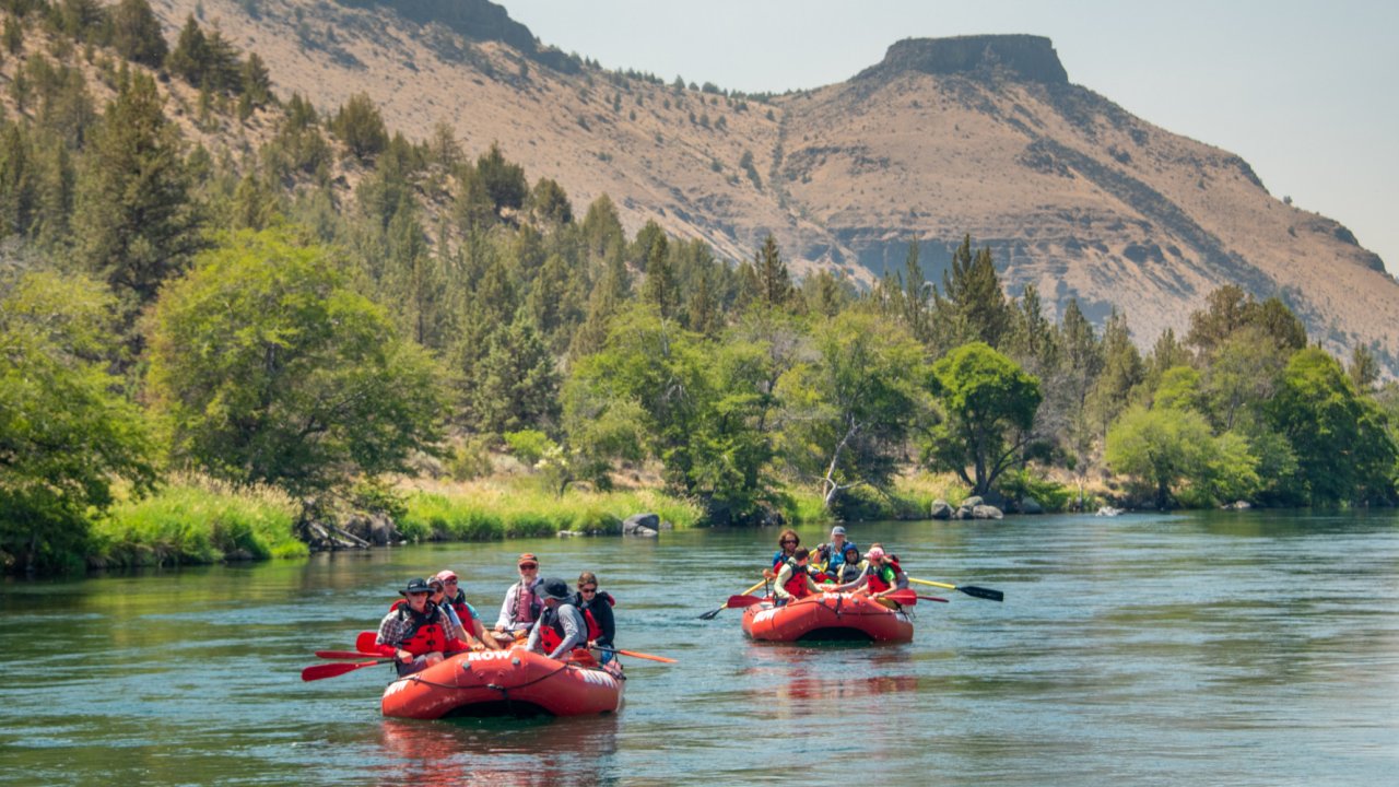 Three red rafts floating along the Deschutes river in Oregon