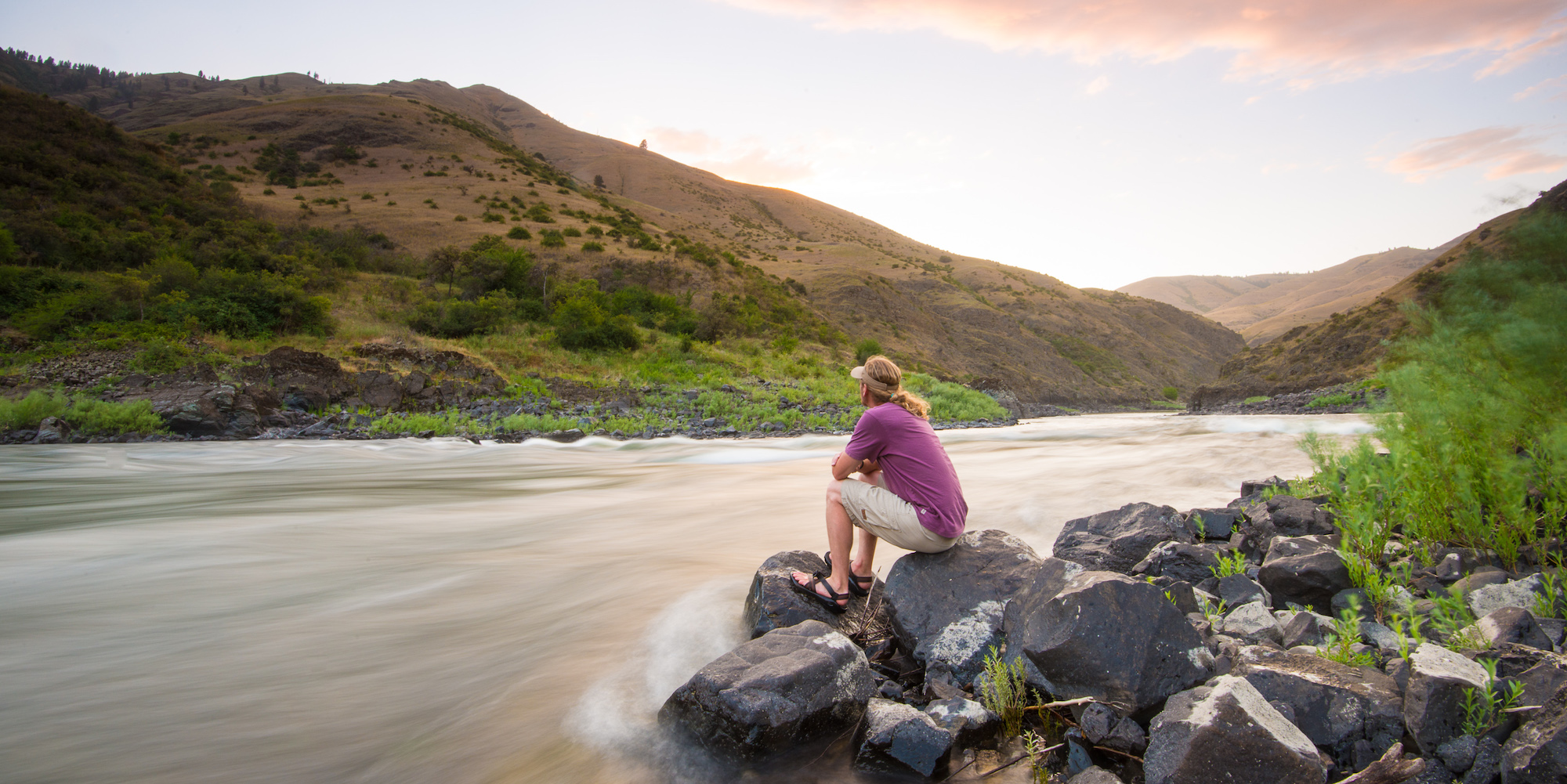 Man sitting along the Salmon River looking out at the sunset