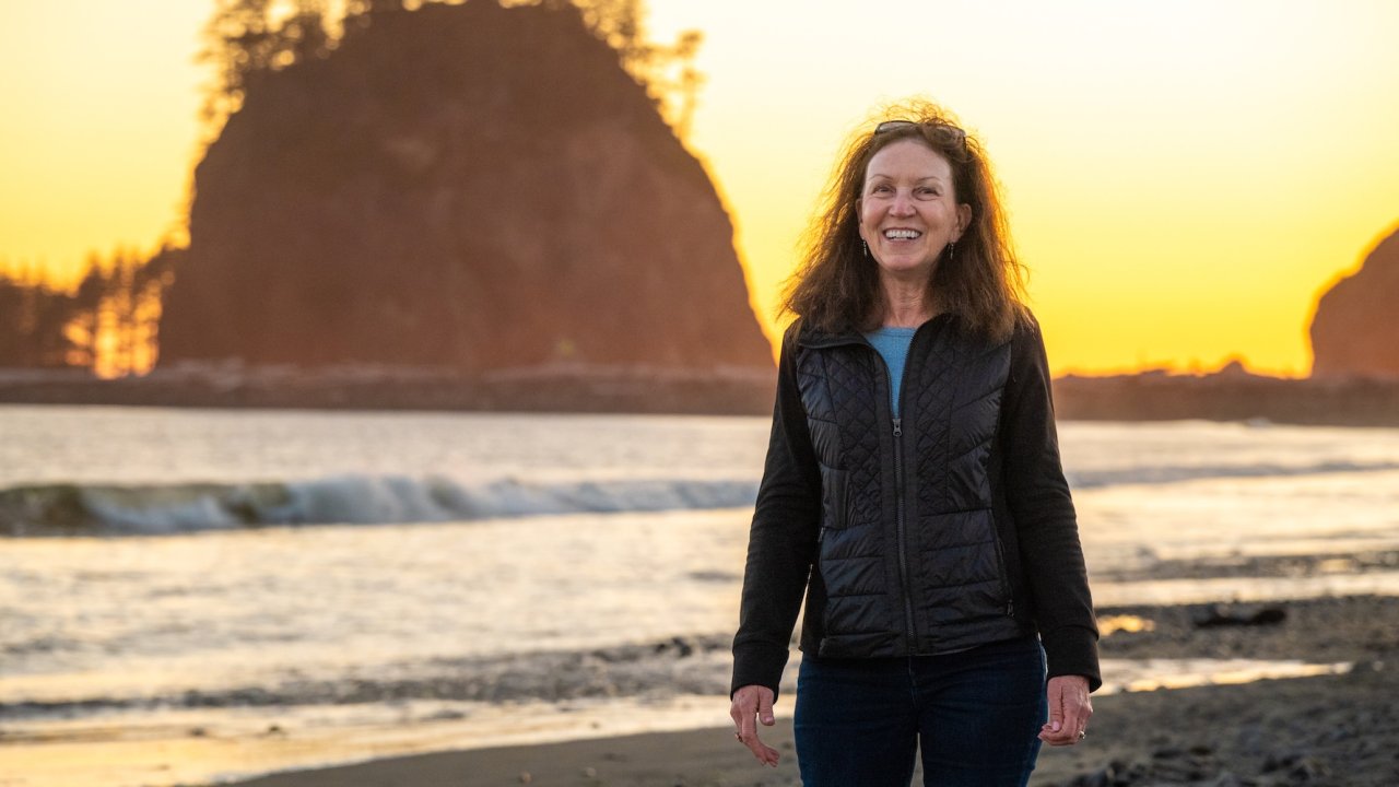 Woman smiling at sunset on the beach of Washington’s Olympic Peninsula, a scenic stop on an Olympic National Park e-biking adventure.
