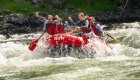 Paddling through a rapid on a ROW branded red raft