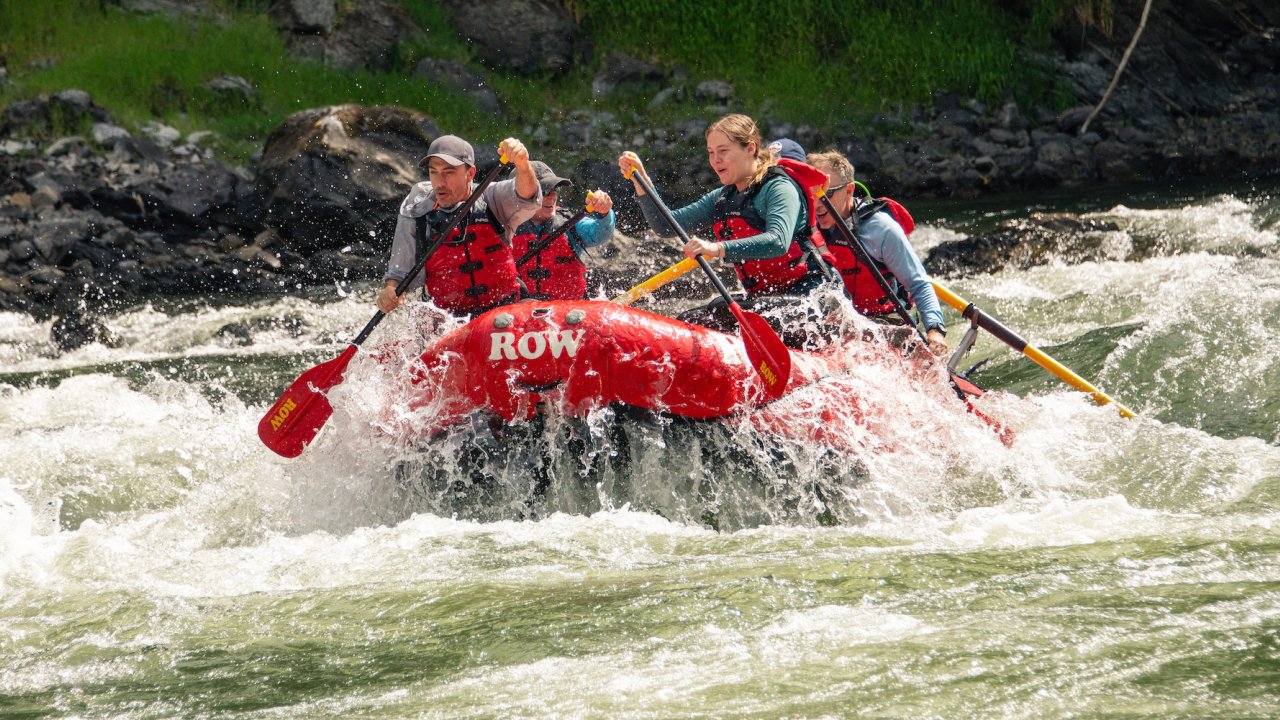 Paddling through a rapid on a ROW branded red raft