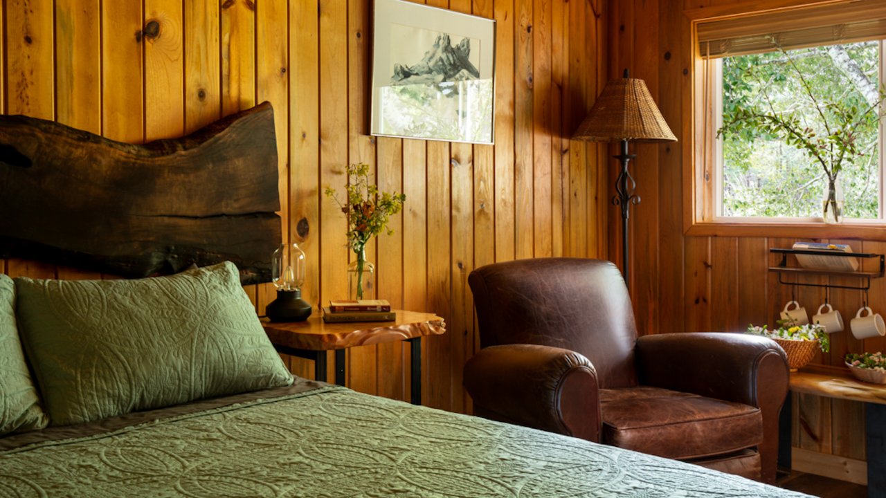 Queen bed and rocking chair in the corner of a cozy cabin in Oregon