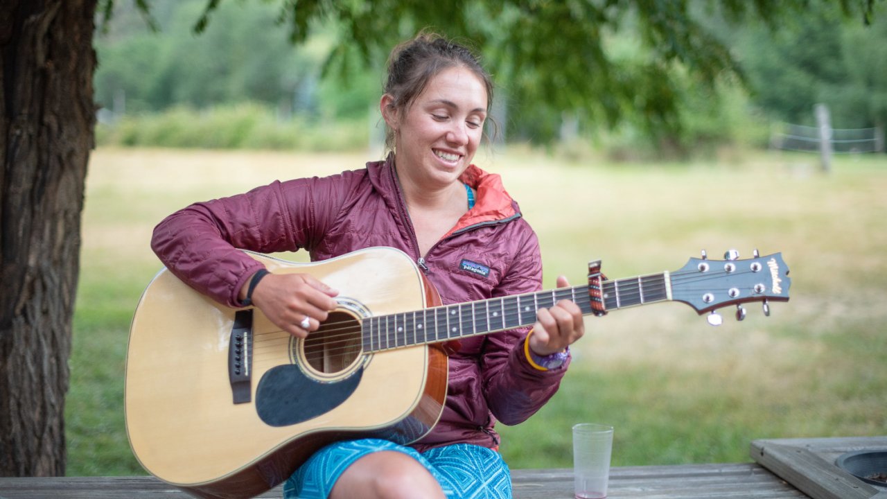 girl sitting on table playing guitar