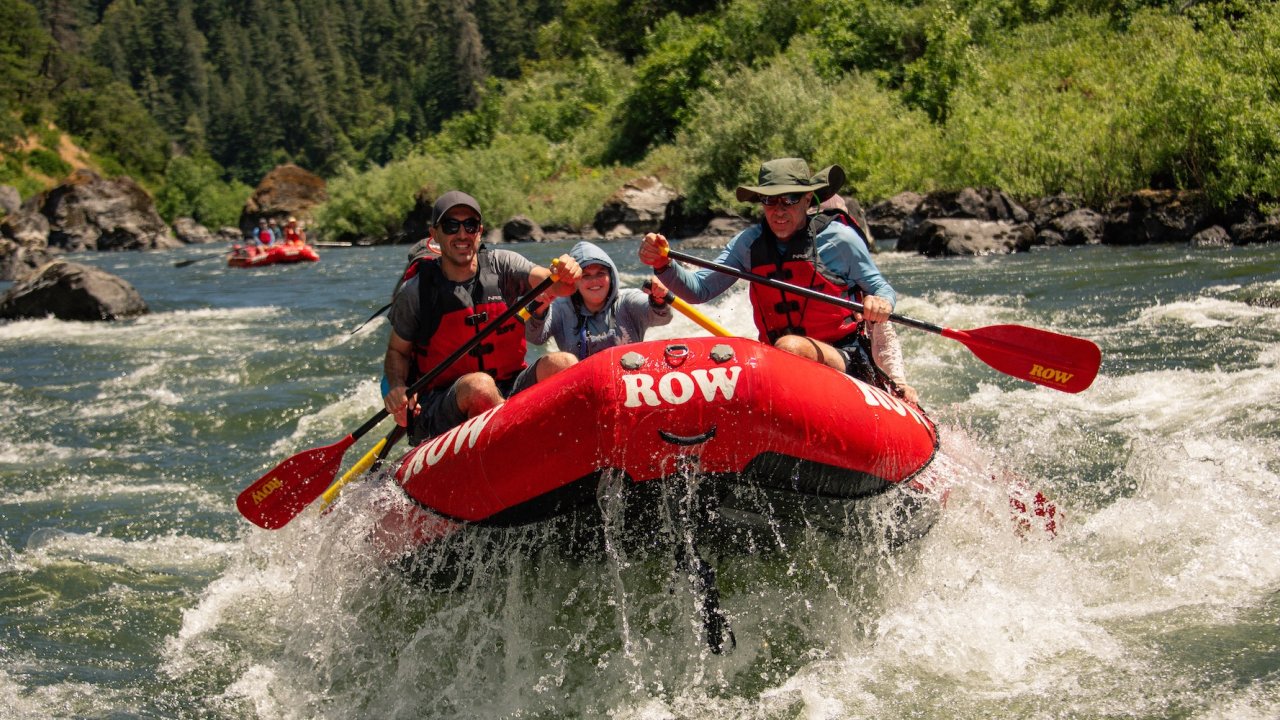 Group rafting through splashing rapids on the Rogue River in Oregon, highlighting the excitement and teamwork of guided Rogue River rafting trips.