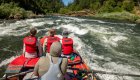 View from the back of a raft as adventurers ride rapids on the Rogue River in Oregon, capturing the beauty and excitement of Oregon rafting vacations.