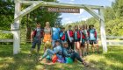 Group of whitewater rafters sitting under a sign at a lodge next to the river