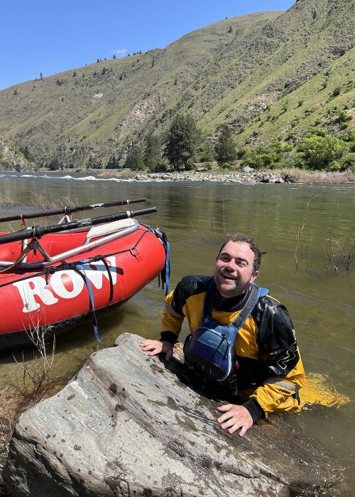 ROW River guide in the river near a red raft.