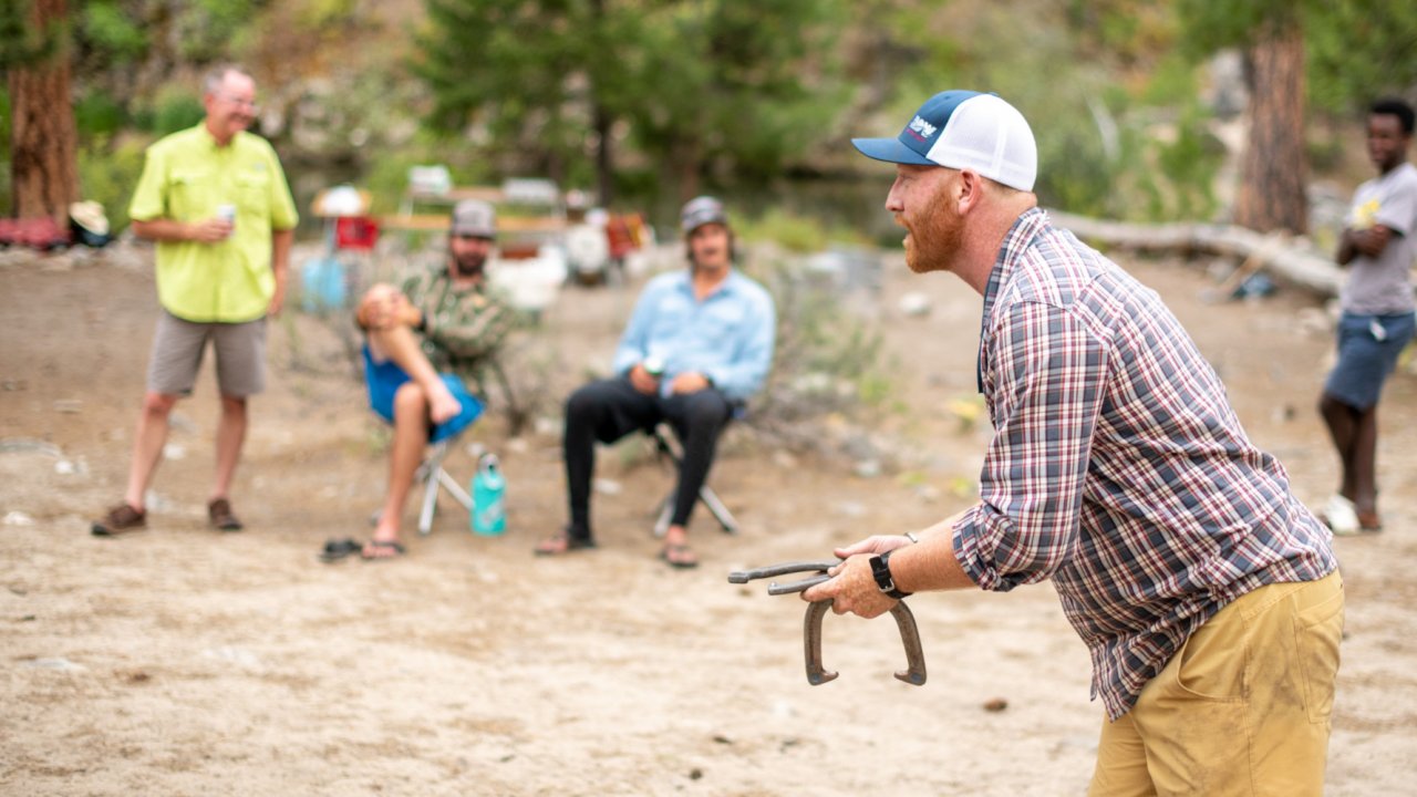 man throwing horseshoes on wooded beach