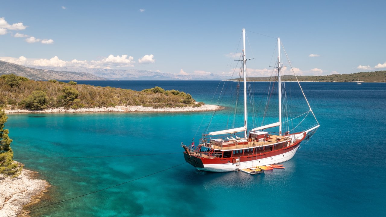 A yacht anchored in the calm waters of the Adriatic Sea at sunset.