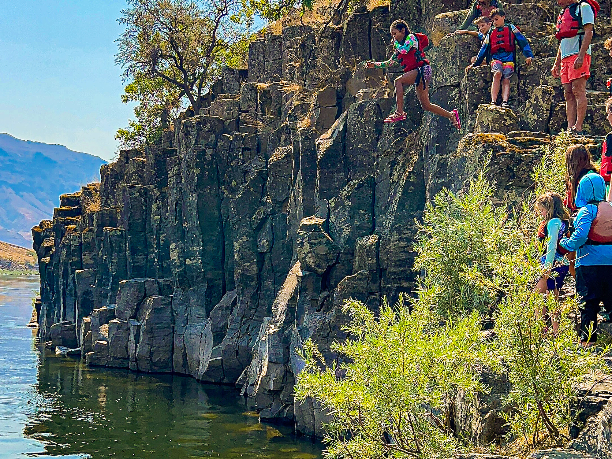 Kid jumping off a rock and into the Salmon River on a sunny summer day