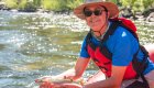 Person leaning over a red rafting holding a fish just out of the Salmon River