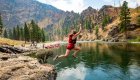Guest jumping off a riverside cliff into the Middle Fork of the Salmon River in Idaho, enjoying a thrilling moment during a guided rafting and adventure tour.