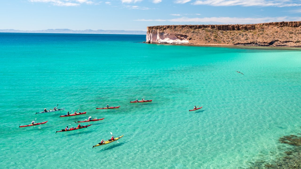 Kayakers paddling across crystal clear water in La Paz, Baja.