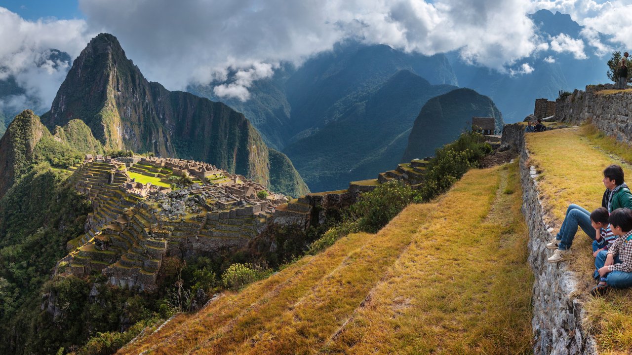 A group of people sitting at Machu Picchu observing and admiring