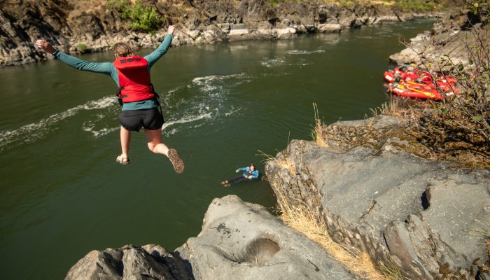 Girl jumping off a rock into a swimming pool along the Rogue River in Oregon